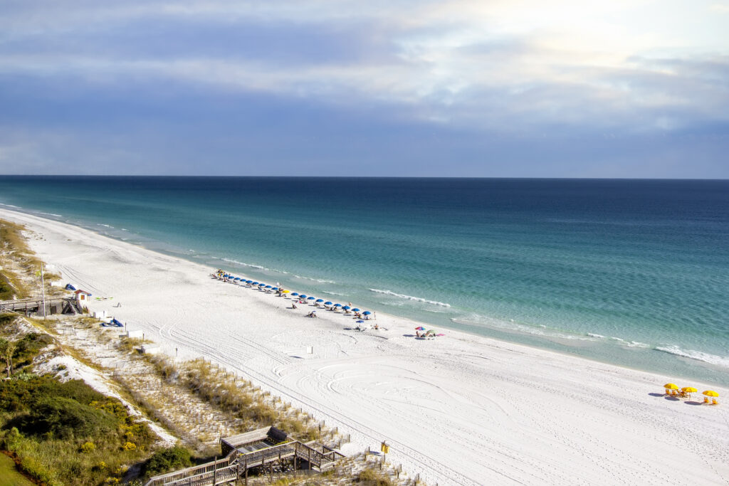 aerial view of Destin Beach, beach-goers under umbrellas on the shore next to the ocean