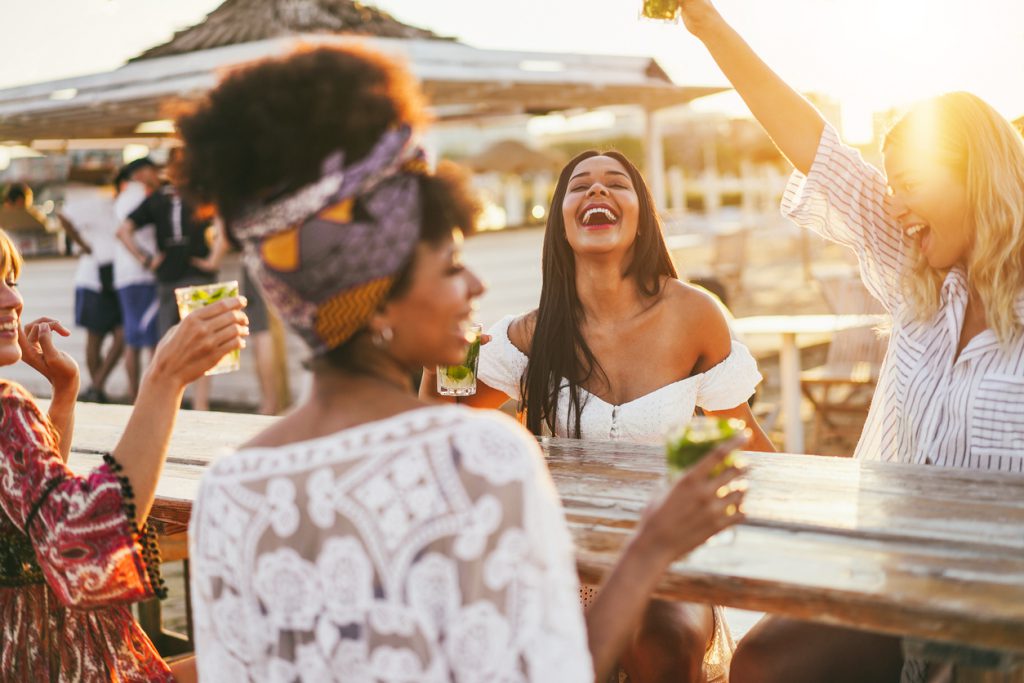 girls laughing at beachfront bar sharing a drink