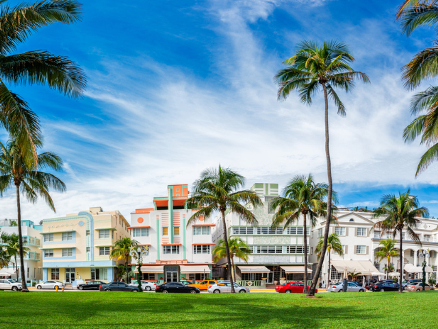 Colorful Miami South Beach buildings with palm trees and green grass