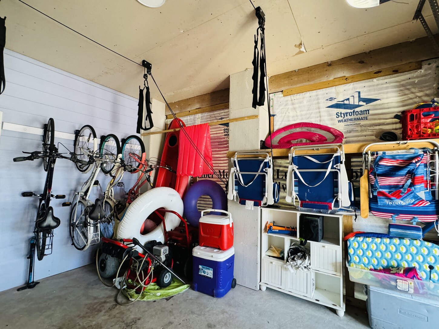 Garage with bikes, beach chairs, toys, coolers, and floats